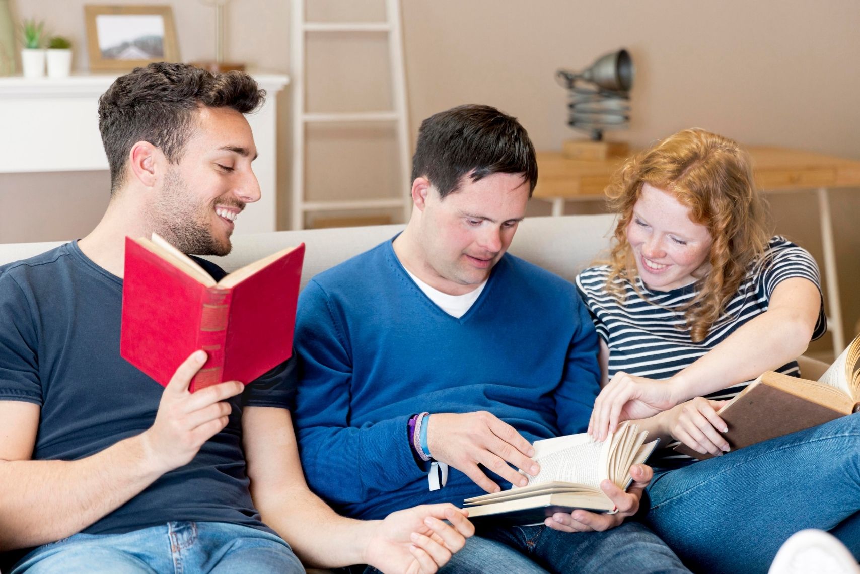 Three young people sit on a couch, each engrossed in their own book, creating a cozy reading atmosphere.